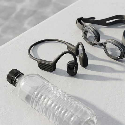 Swym+ black bone conduction headphones on a pool deck next to a water bottle and swimming goggles.