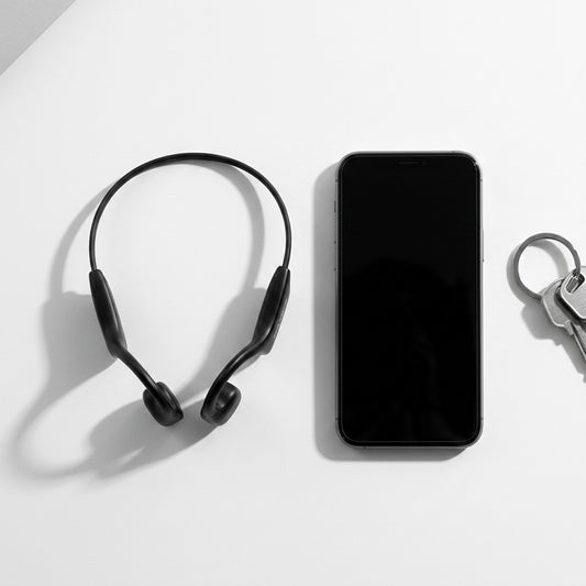 Black OPN Sound Osso bone conduction headphones shown next to a smartphone and keys for scale.