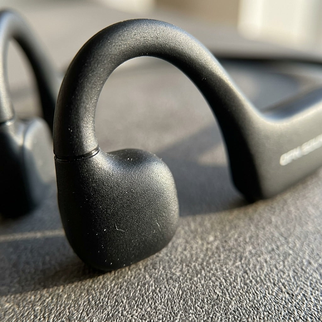 Macro detail of OPN Sound Osso bone conduction headphones showing the matte black transducer loop and transducer.